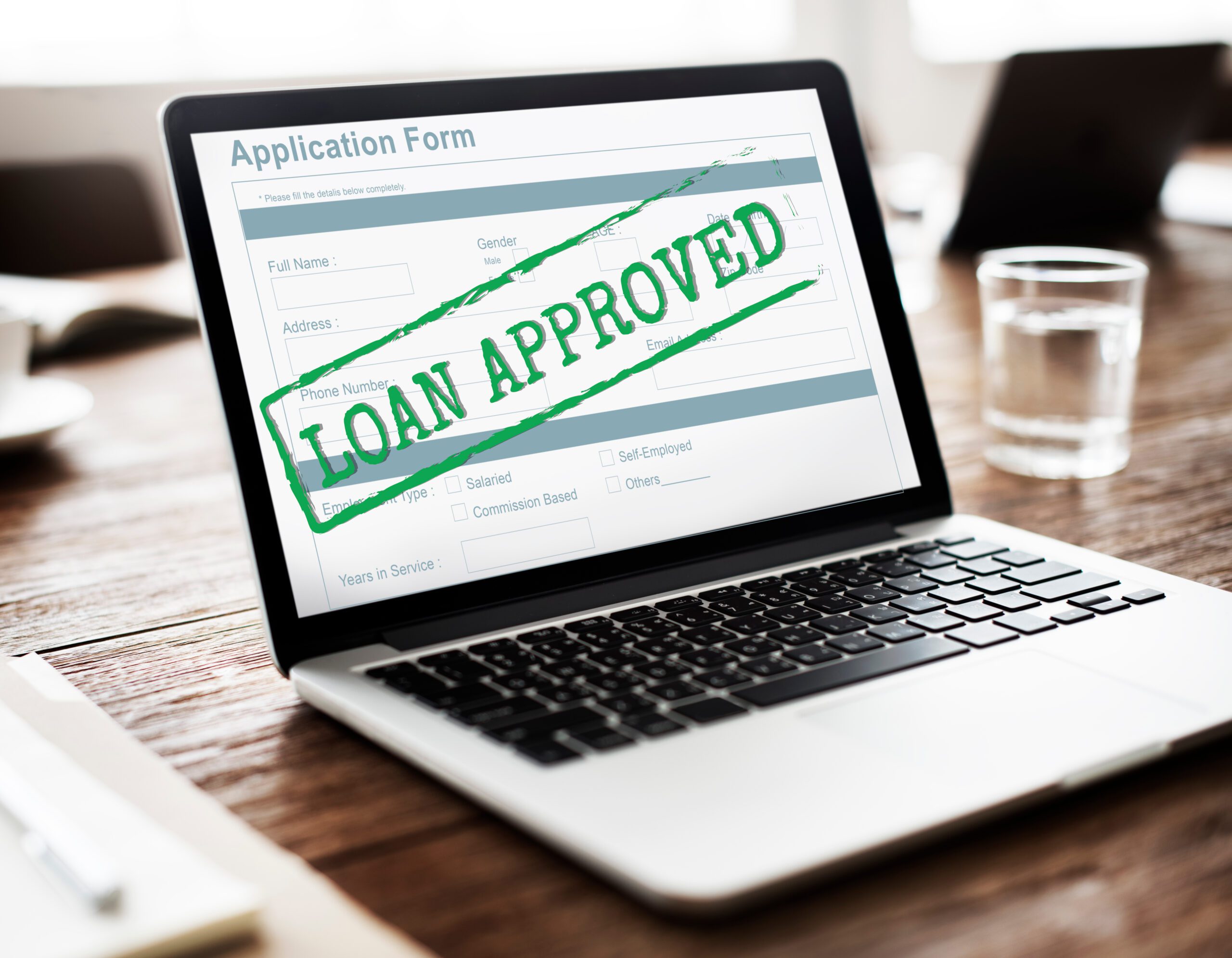 Laptop displaying an application form stamped ‘Loan Approved’, symbolizing contingency fee financing approval for plaintiff law firms.